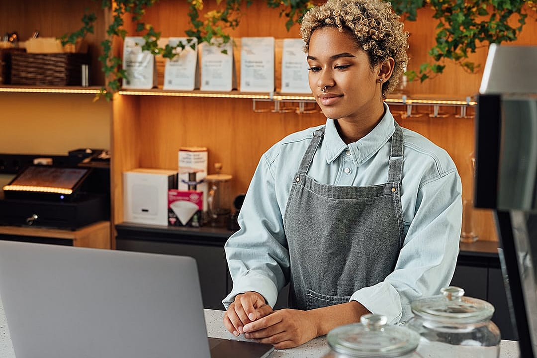 A café owner reviewing business insurance options on her laptop during a short break.